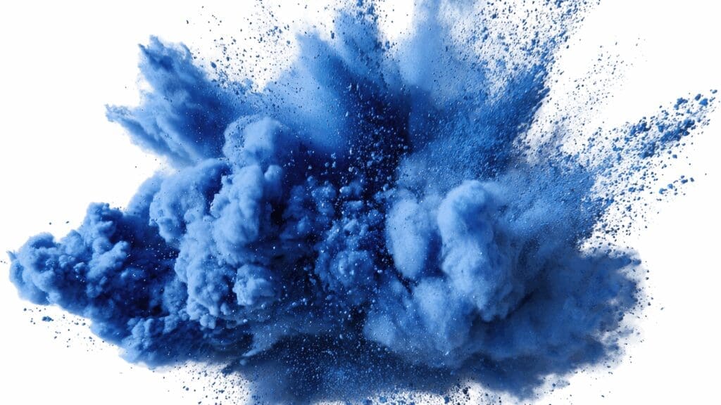 Abstract blue powder explosion and particles dispersing across white background, visually representing the neuroplasticity and brain rewiring central to dopamine coaching.