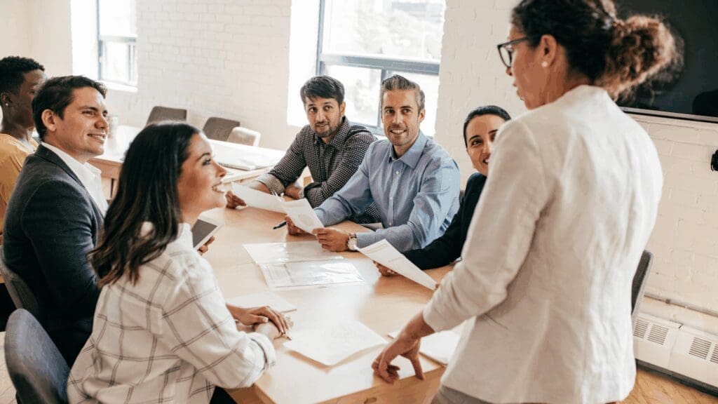 Business leader coaching a diverse team, illustrating teamwork and support in imposter syndrome leadership coaching.