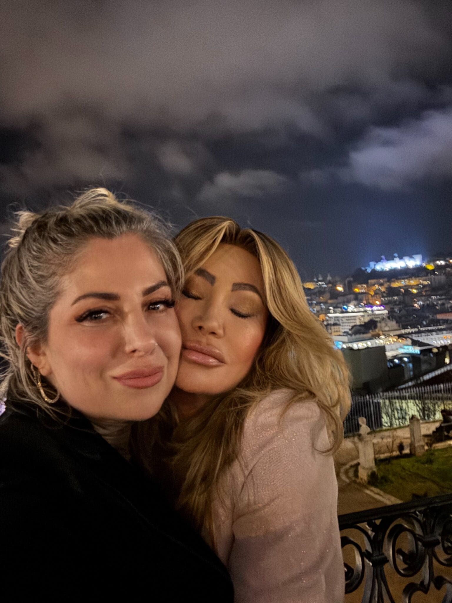 Dr. Sydney Ceruto 35 Dr. Sydney Ceruto embracing close friend Mila at night in Lisbon with city lights showing deep authentic friendship
