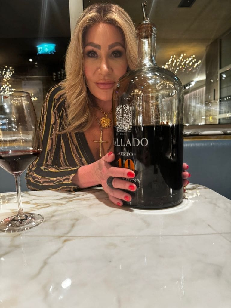 Dr. Sydney Ceruto 47 Dr. Sydney Ceruto seated at an elegant marble table holding a large Jeroboam bottle of Vallado Porto wine