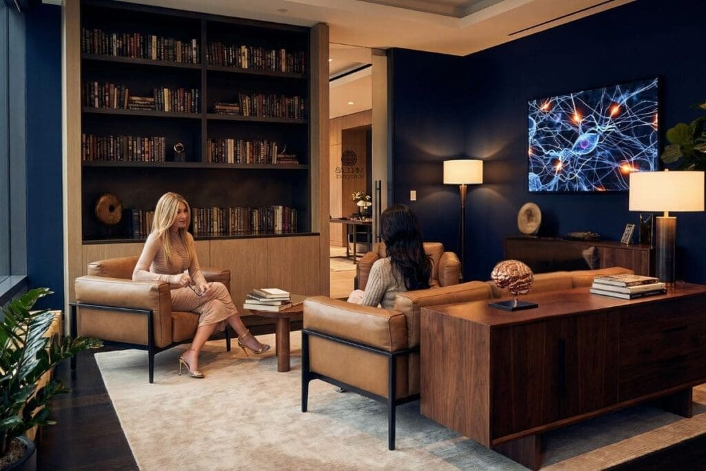 Dr. Sydney Ceruto discussing neuroscience programs with a client in the MindLAB Neuroscience private office with neural pathway display