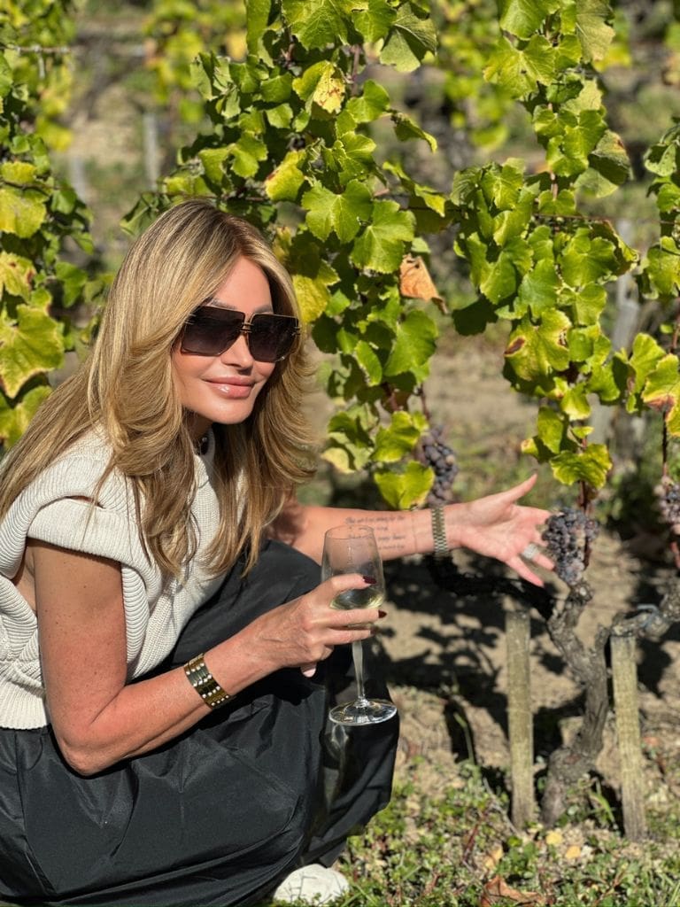 Dr. Sydney Ceruto 44 Dr. Sydney Ceruto holding a glass of wine while touching ripe grapes on the vine in a sunlit vineyard in Sauternes, France